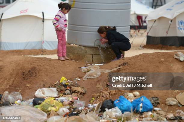 Two girls drink water as Syrian refugees go about their daily business in the Za’atari refugee camp on January 29, 2013 in Mafrq, Jordan. Record...
