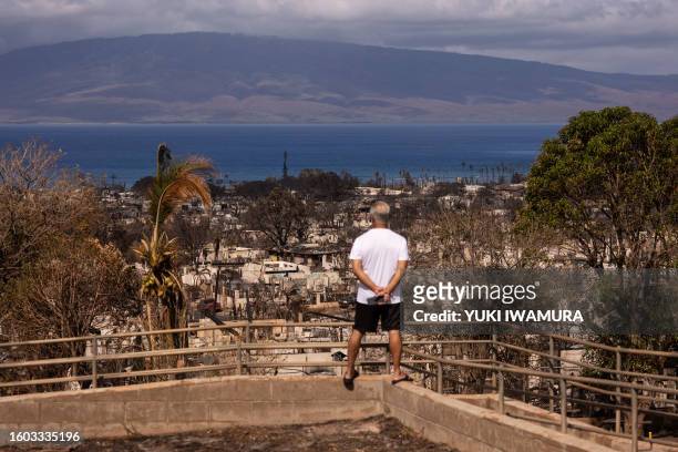 Man looks at burned buildings in the aftermath of the Maui wildfires in Lahaina, Hawaii on August 16, 2023. The number of people known to have died...