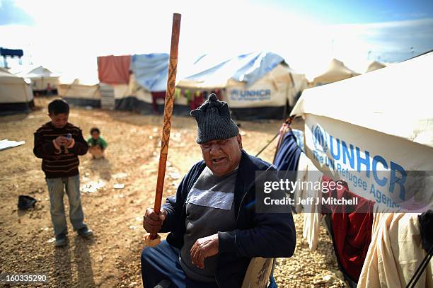 Man gestures with his stick as Syrian refugees go about their daily business in the Za’atari refugee camp on January 29, 2013 in Mafraq, Jordan....
