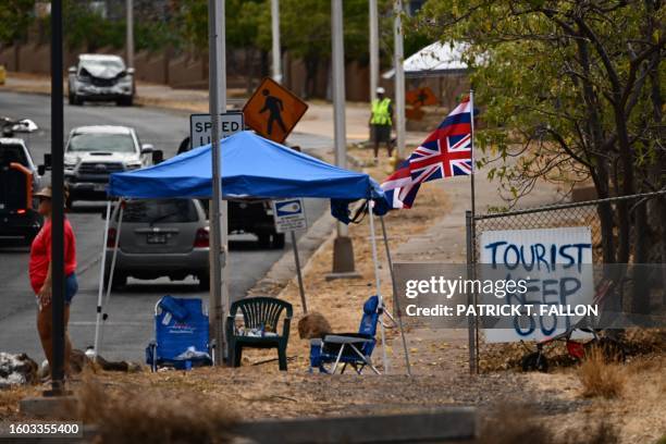 The Flag of Hawaii waves by a sign reading "Tourist Keep Out" in the aftermath of the Maui wildfires in Lahaina, Hawaii, on August 16, 2023. The...