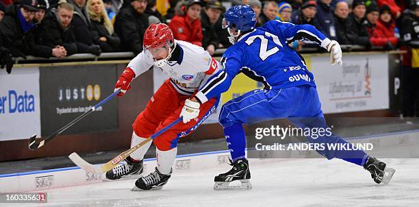 Russia's Sergey Lomanov is attacked by Finland's Samuli Helavuori during the Bandy World Championship match between Finland and Russia in...