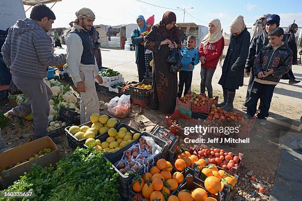 People buy fruit and vegetables as Syrian refugees go about their daily business in the Za’atari refugee camp on January 29, 2013 in Mafraq, Jordan....