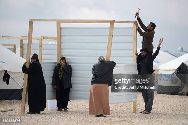 Men and women construct a temporary kitchen as as Syrian refugees go about their daily business in the Za’atari refugee camp on January 29, 2013 in...