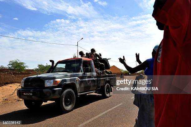 People cheer on the side of the road on January 29, 2013 in Ansongo, a town south of the northern Malian city of Gao, as Niger troops enter the city....