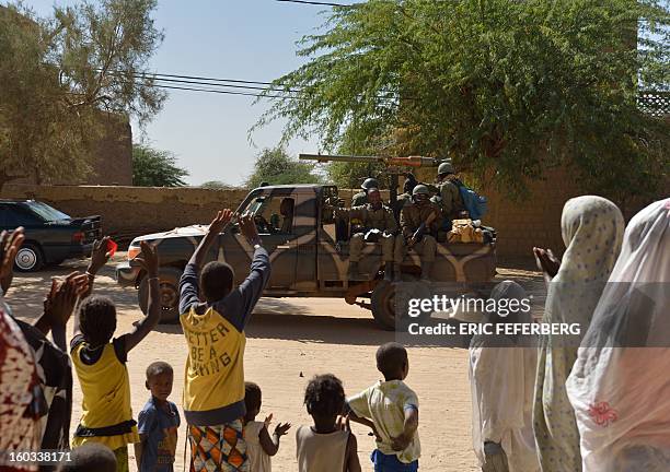 People wave as Malian soldiers on a pick-up truck cross on January 29, 2013 Timbuktu after French-led troops freed the northern desert city on...