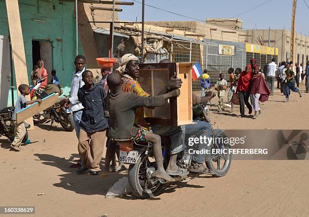 Looters leave with a cabinet on a motocycle on January 29, 2013 in Timbuktu after French-led troops freed the northern desert city on January 28 from...