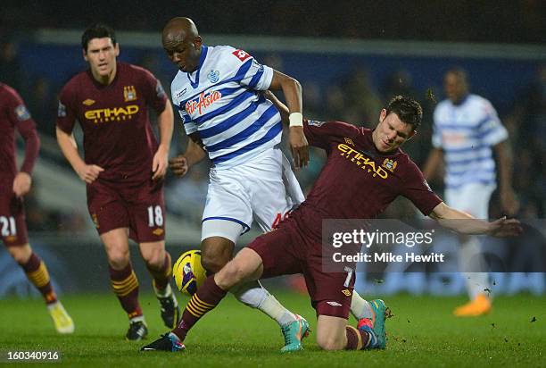 Stephane Mbia of QPR is tackled by James Milner of Manchester City during the Barclays Premier League match between Queens Park Rangers and...