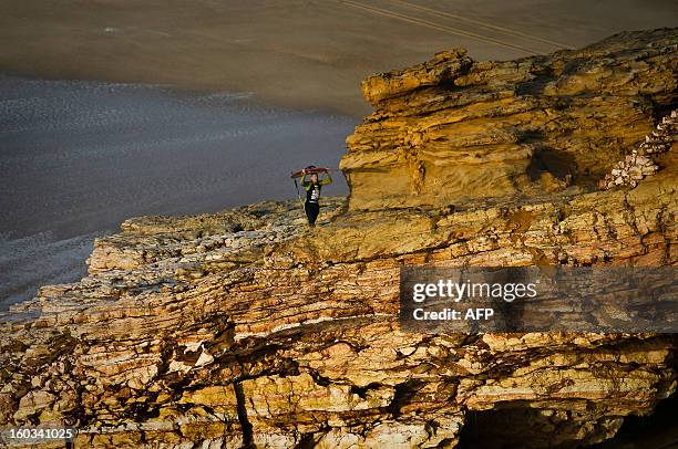 Hawaiian surfer Garrett McNamara carries his surfboard as he leaves the beach after a surf session at Praia do Norte in Nazare on January 29, 2013....