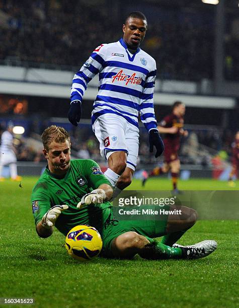 Goalkeeper Joe Hart of Manchester City smothers the ball as Stephane Mbia of QPR closes in during the Barclays Premier League match between Queens...