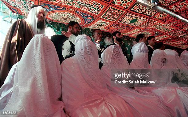 Jordanian grooms and brides prepare for a mass wedding ceremony at a school July 20, 2001 in Amman. The wedding ceremony for 72 couples was organized...