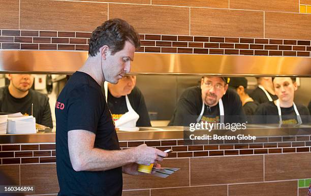 Bobby Flay checks his cell phone during the opening of his newest location of Bobby's Burger Palace in the Burlington Mall on Sunday, Jan. 27, 2013.