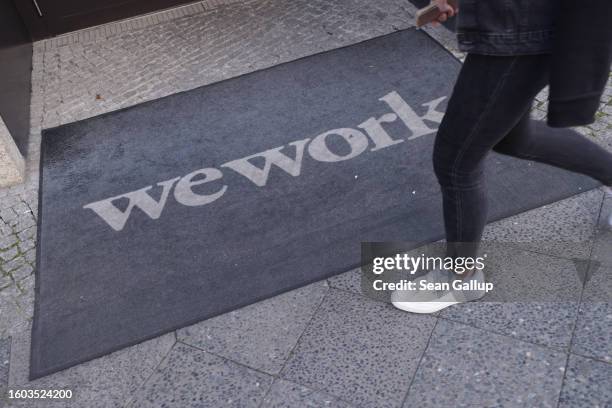 Person walks past the logo of WeWork on a doormat outside a building where the company offers co-working space on August 09, 2023 in Berlin, Germany....