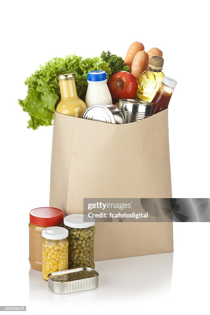 Brown bag full of groceries sits on white background