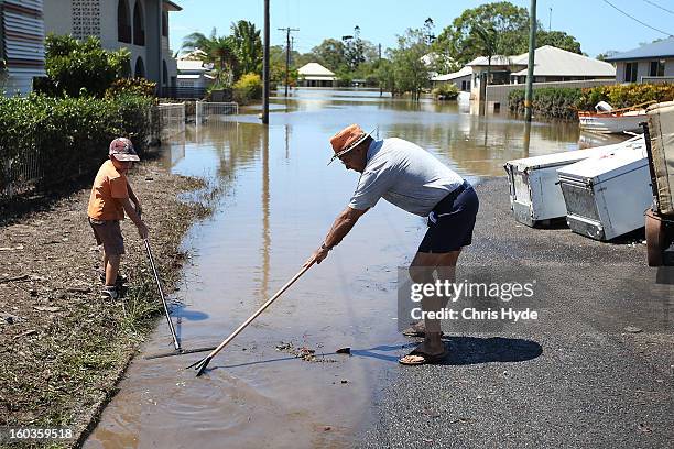 Residents clean up debris in their street as parts of southern Queensland experiences record flooding in the wake of Tropical Cyclone Oswald on...