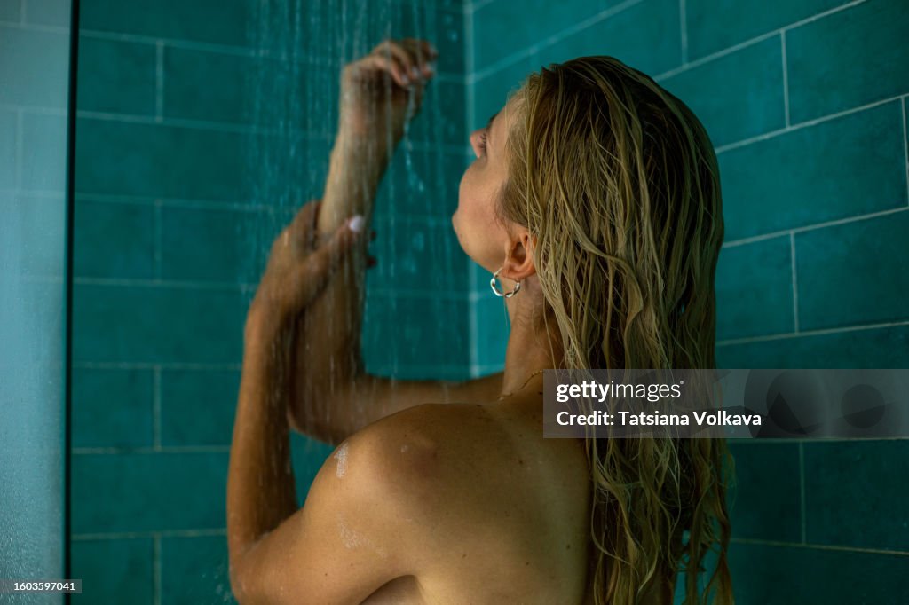 Beautiful lady immerses herself in revitalizing flow of warm shower caressing tired hands