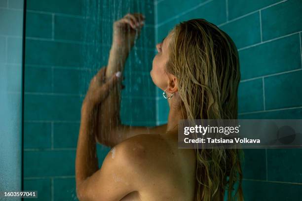 beautiful lady immerses herself in revitalizing flow of warm shower caressing tired hands - douche stockfoto's en -beelden