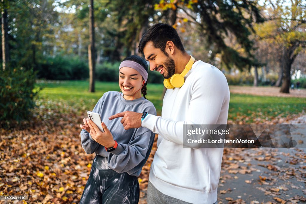 Young sporty couple using smartphone