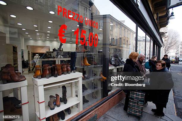 Pedestrians stand and talk outside a shoe store advertising a sale in its window display in Turin, Italy, on Tuesday, Jan. 29, 2013. Italy sold 8.5...