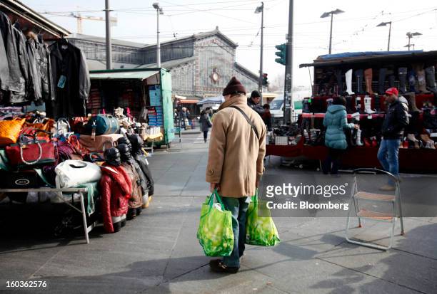 Pedestrian holds his goods in shopping bags as he stands at street market stall in Turin, Italy, on Tuesday, Jan. 29, 2013. Italy sold 8.5 billion...