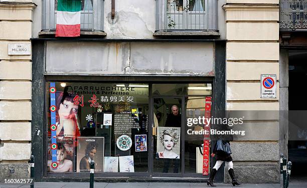 Pedestrian speaks on her mobile phone as she passes a hairdresser's shop in Turin, Italy, on Tuesday, Jan. 29, 2013. Italy sold 8.5 billion euros of...