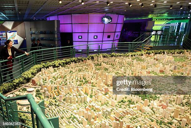 Woman points at a model of the city of Shanghai at the Shanghai Urban Planning Exhibition Center in Shanghai, China, on Tuesday, Jan. 29, 2013....