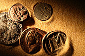 Ancient coins laying in golden sand