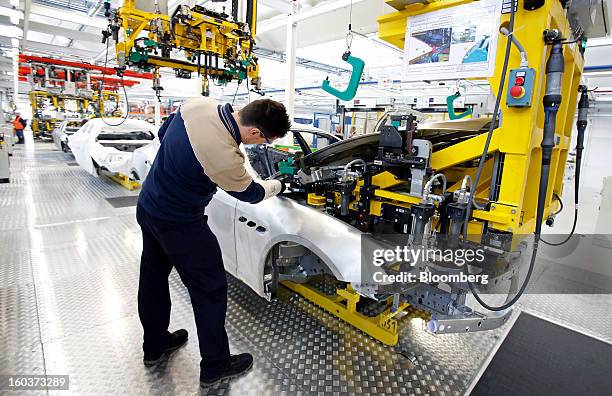 An employee oversees the robot-assisted assembly of a hood to a Maserati Quattroporte luxury automobile at Fiat SpA's Grugliasco factory in Turin,...