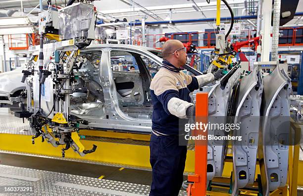 An employee prepares to mount a rear passenger door onto the bodyshell of a Maserati Quattroporte luxury automobile as it travels along the...