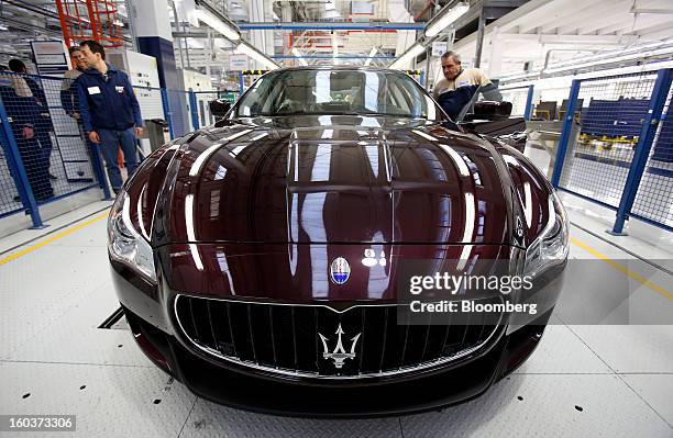 Employees check the wheel alignment during the production of a Maserati Quattroporte luxury automobile at Fiat SpA's Grugliasco factory in Turin,...