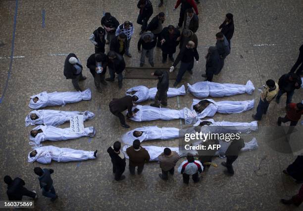 Syrians gather around the bodies of civilians, who were executed and dumped in the Quweiq river, lying at the courtyard of the Yarmuk school in the...