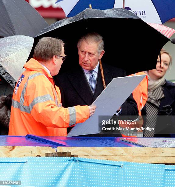 Prince Charles, Prince of Wales shelters under an umbrella as he views the Crossrail development site before travelling on a Metropolitan line...