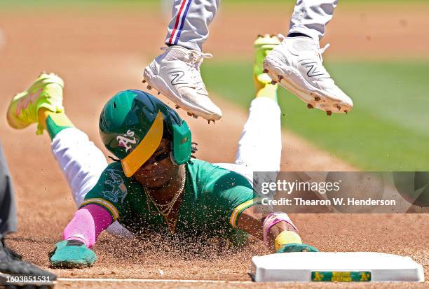 Esteury Ruiz of the Oakland Athletics steals third base sliding under the cleats of Josh Smith of the Texas Rangers in the bottom of the third inning...