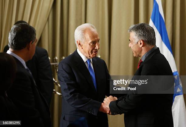 Israel's President Shimon Peres shakes hands with Yair Lapid, leader of the Yesh Atid party, speaks during their meeting on January 30, 2013 in...