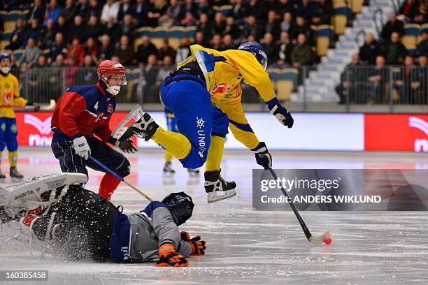 Sweden's Patrik Nilsson jumps over Norway's goalie Christopher Smerkerud during the Bandy World Championship match between Sweden and Norway in...