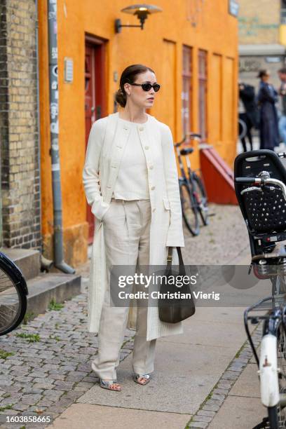 Annabel Rosendahl wears creme white coat, pants, shirt, brown bag, silver heels outside Remain during the Copenhagen Fashion Week Spring/Summer 2024...