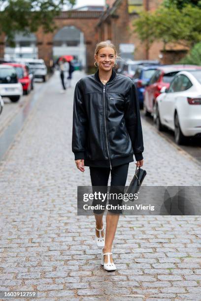 Hanna Stefansson wears black oversized zipper leather jacket, cropped pants, bag, white heels outside Skall Studio during the Copenhagen Fashion Week...