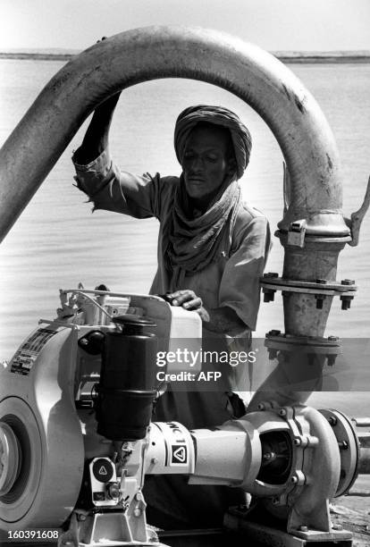 Picture released in 1989 of Aliou Mussa, a farmer from the West African Songhai tribe, inspects a horsepower diesel pump that draws water from the...