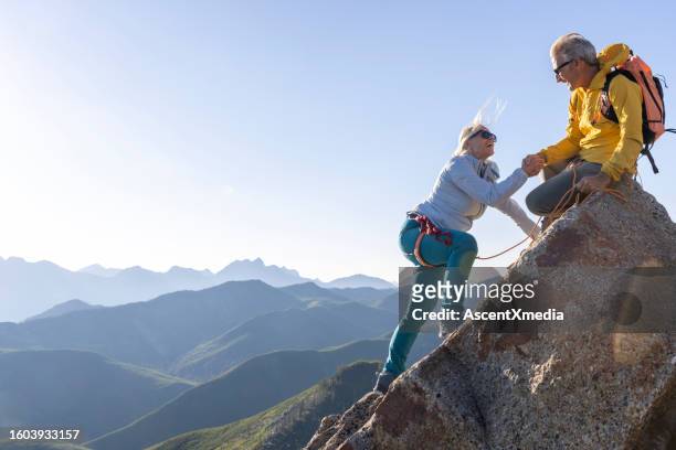 mature couple climb to mountain summit - climbing stock pictures, royalty-free photos & images