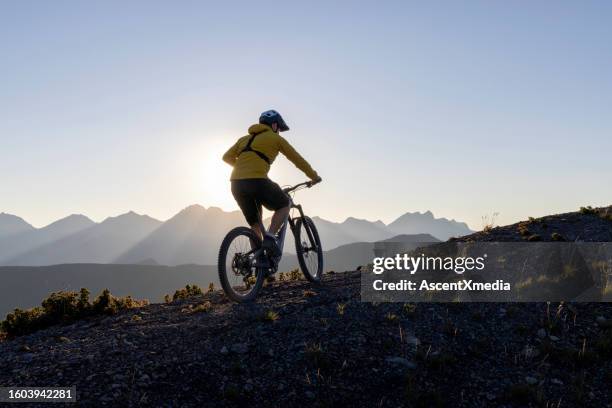 male mountain biker ascends high mountain ridge - mid adult stock pictures, royalty-free photos & images