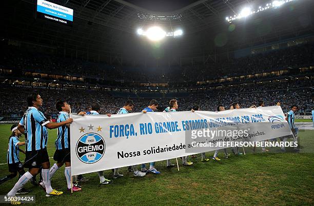 Brazil's Gremio football team enters the field carrying a banner in homage to the victims of a fire in Santa Maria, before the start of their Copa...