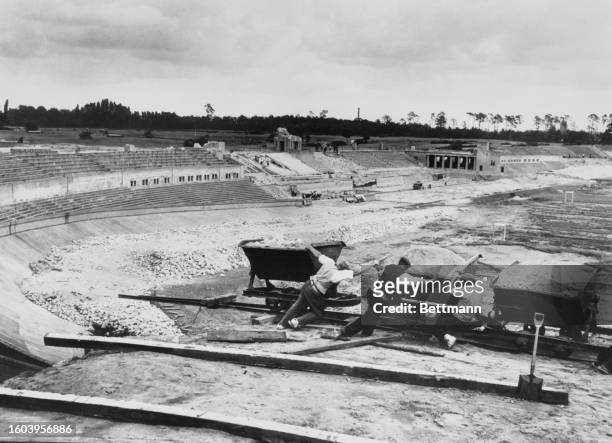 Workers haul carts of material during the construction of the Olympic Stadium, Germany, June 1935.