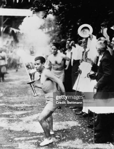 The first torch-bearer out of 3000 to bear the Olympic torch hands the torch over to the second runner, Olympia Greece, 27th July 1936.