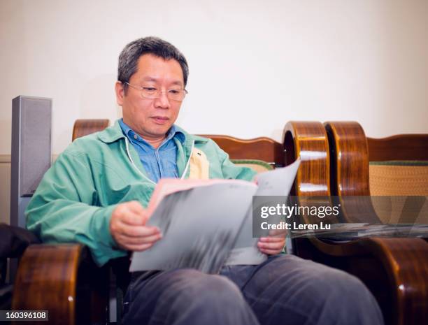 man reads magazine in livingroom - holding magazine stock-fotos und bilder