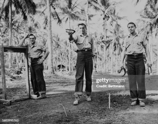 C D.M. Seeley, QM 2/c J.C. Bounds and BM 1/c E.W. Martin play a game of 'Horseshoes' after being rescued from the light cruiser "Helena", South...