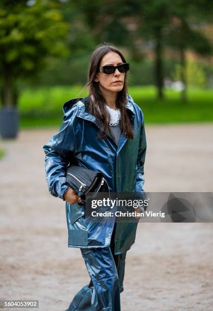 Guest wears blue rain jacket, pants outside OpéraSport during the Copenhagen Fashion Week Spring/Summer 2024 on August 09, 2023 in Copenhagen,...