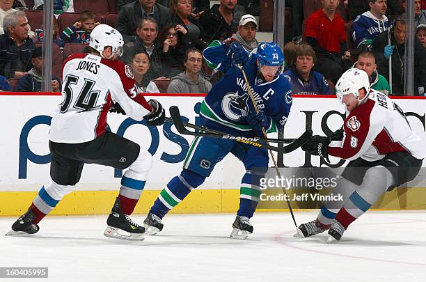 David Jones and Jan Hejda of the Colorado Avalanche combine to check Henrik Sedin of the Vancouver Canucks during their NHL game at Rogers Arena...