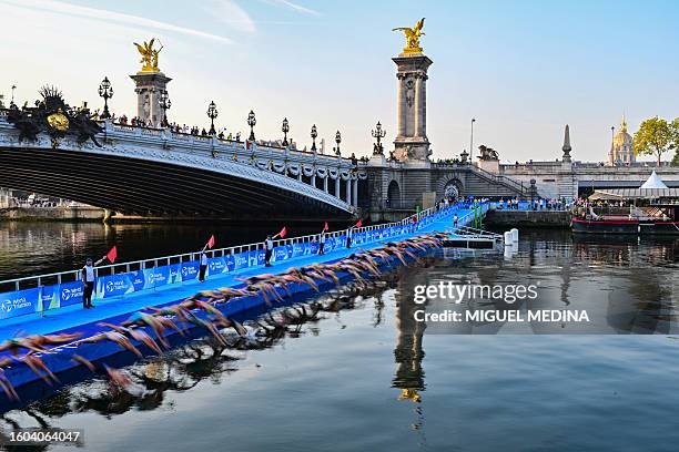 Triathlon athletes start to compete swimming in the Seine river next to the Alexandre III bridge during a Test Event for the women's triathlon for...