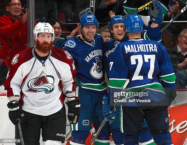 Goal scorer Maxim Lapierre of the Vancouver Canucks is congratulated by teammates Aaron Volpatti and Manny Malhotra as Greg Zanon of the Colorado...