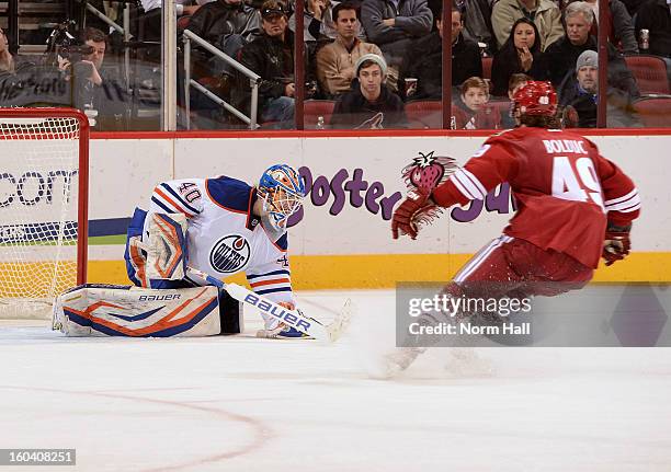 Devan Dubnyk of the Edmonton Oilers covers up the puck as Alexandre Bolduc of the Phoenix Coyotes looks for a rebound at Jobing.com Arena on January...