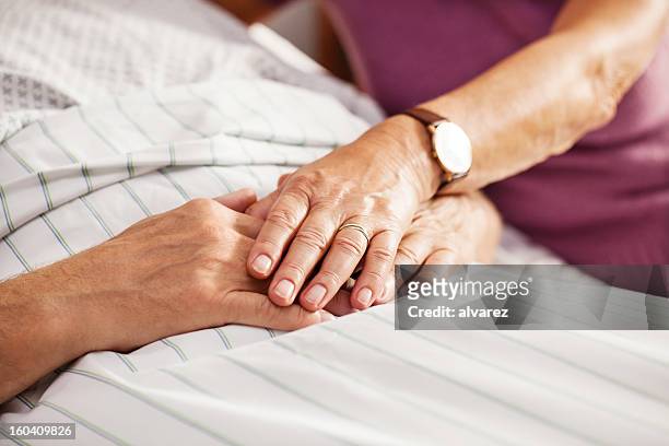 senior patient holding his wifes hand - man in hospital stockfoto's en -beelden
